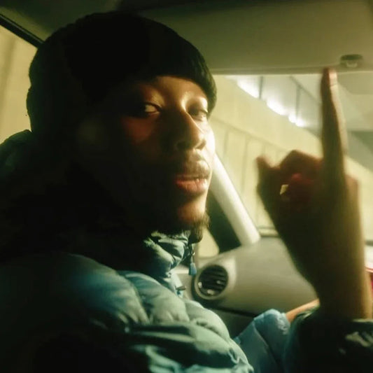 Man wearing a black beanie and blue puffer jacket inside a car.