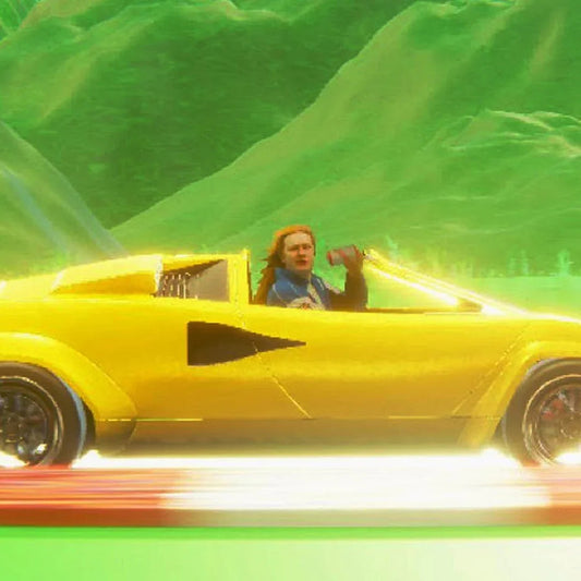A person with long hair driving a yellow sports car through a green landscape.